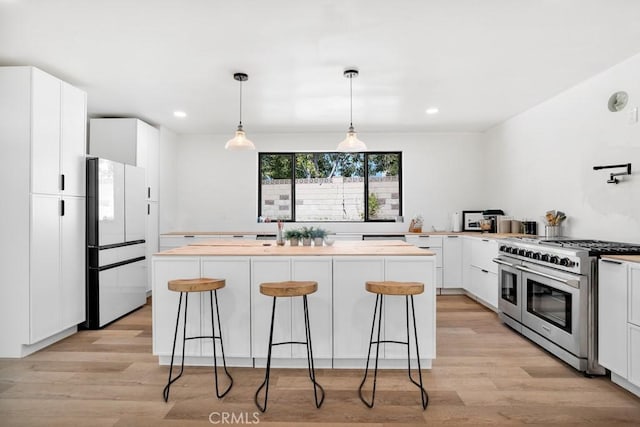 kitchen with light wood-type flooring, freestanding refrigerator, double oven range, and a kitchen island