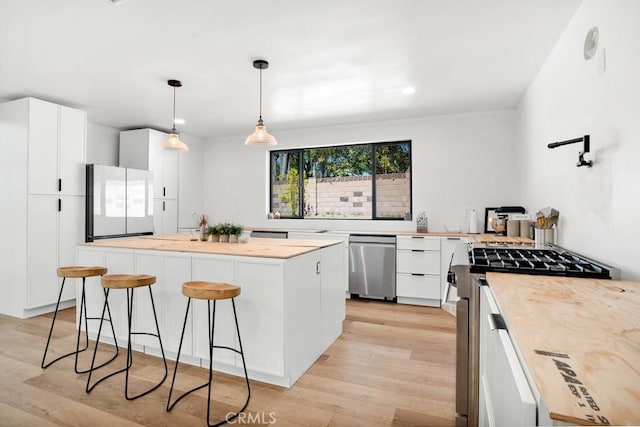 kitchen featuring light wood-style flooring, a kitchen island, white cabinetry, and stainless steel appliances