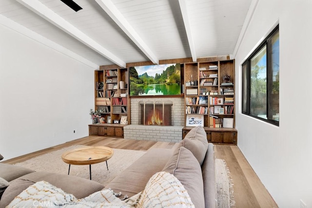 living room with wood finished floors, a fireplace, and beam ceiling
