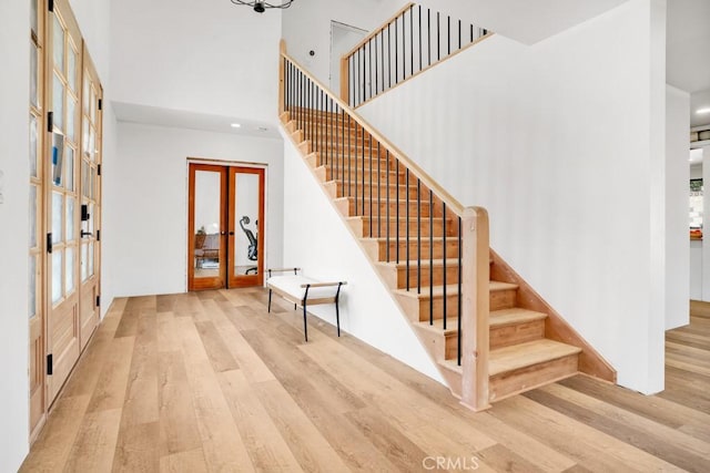 stairway featuring french doors, recessed lighting, a high ceiling, and wood finished floors