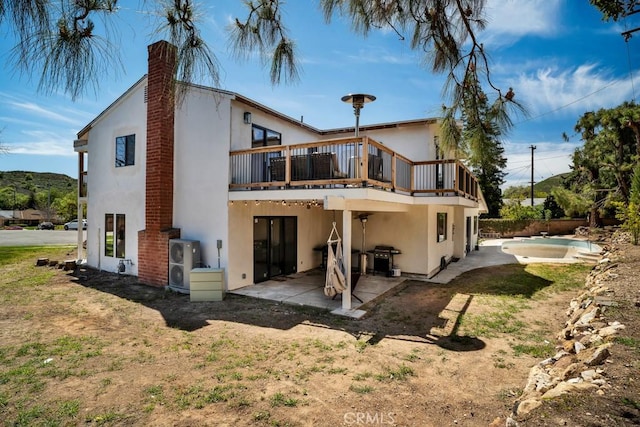 back of house featuring a patio area, a chimney, a fenced in pool, and stucco siding