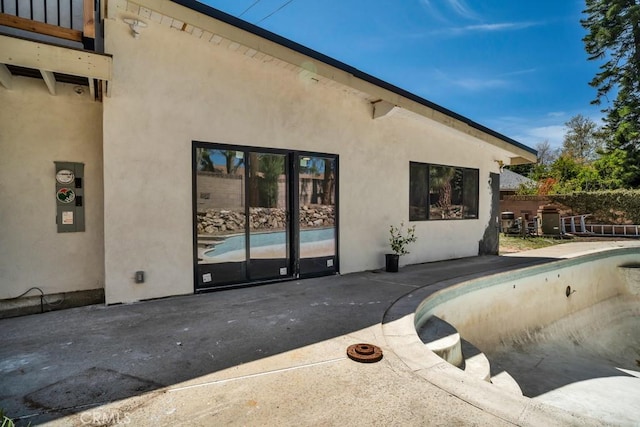 exterior space featuring an empty pool, a patio, and stucco siding