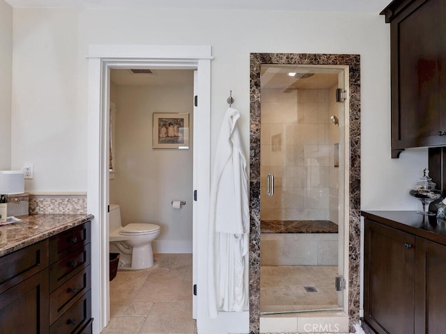 bathroom featuring toilet, baseboards, and a stall shower