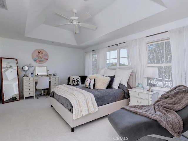bedroom with visible vents, a tray ceiling, a ceiling fan, and light carpet