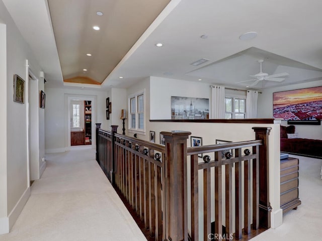 hallway with visible vents, a raised ceiling, an upstairs landing, recessed lighting, and light carpet