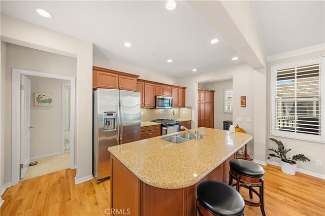 35 Jonquil, Irvine, CA 92618 - kitchen with stainless steel appliances, a sink, light wood-style flooring, baseboards, and a kitchen island with sink