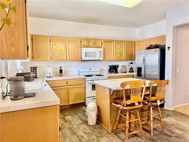 10506 Lee Ave, Adelanto, CA 92301 - kitchen featuring light brown cabinetry, white appliances, a breakfast bar area, a center island, and tile countertops