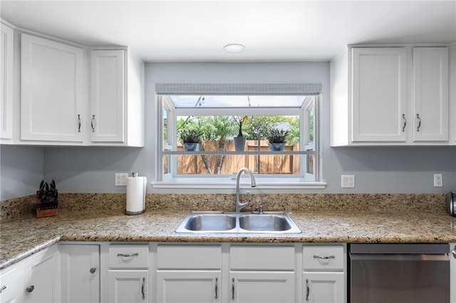 kitchen featuring dishwasher, a sink, and white cabinetry