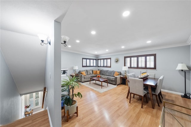 living area with crown molding, a healthy amount of sunlight, light wood finished floors, and recessed lighting