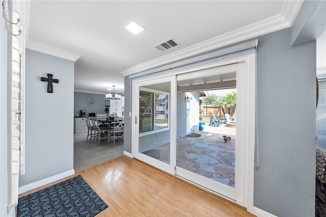 entryway featuring visible vents, baseboards, an inviting chandelier, crown molding, and wood finished floors
