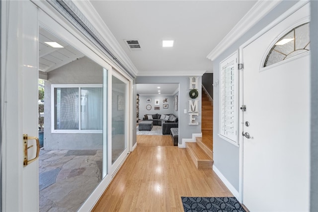 entrance foyer with stairway, light wood-style flooring, visible vents, and crown molding