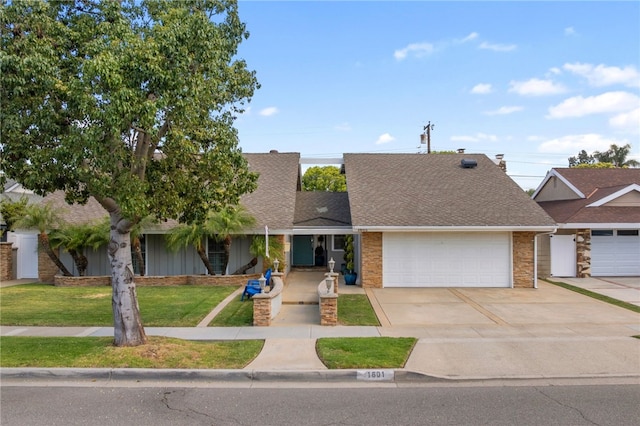 view of front facade featuring a shingled roof, a garage, driveway, and a front lawn