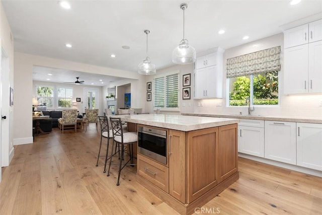 kitchen featuring recessed lighting, open floor plan, light wood-style flooring, and a sink