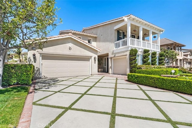 view of front facade featuring stucco siding, concrete driveway, a balcony, and a tile roof