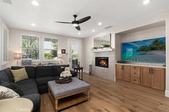 living room featuring light wood finished floors, recessed lighting, visible vents, and a fireplace