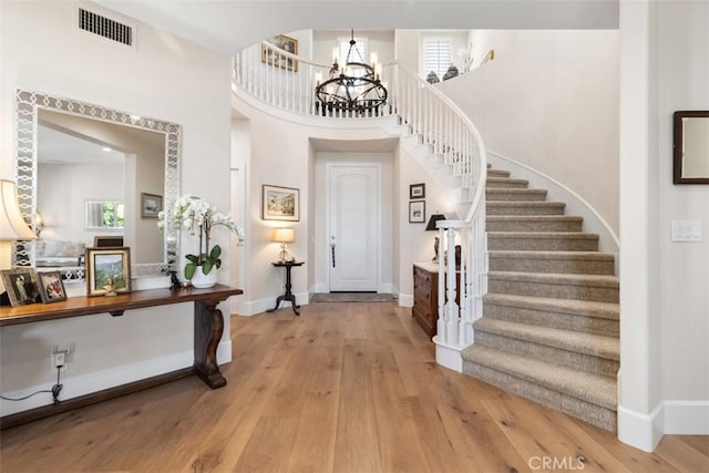 entryway featuring stairway, wood-type flooring, baseboards, visible vents, and a notable chandelier