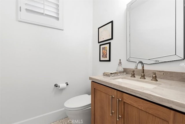 half bathroom featuring baseboards, toilet, and vanity