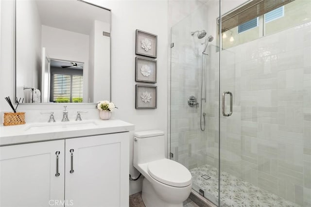 bathroom with toilet, vanity, and a shower stall