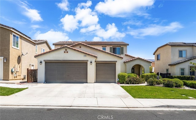 mediterranean / spanish home featuring an attached garage, driveway, stucco siding, and a tile roof