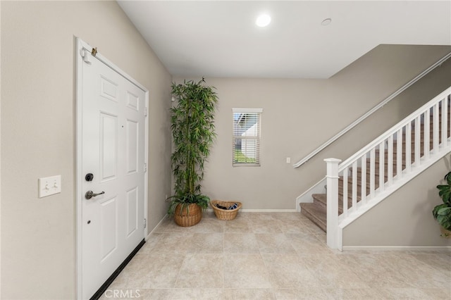 entryway with light tile patterned floors, baseboards, and stairway