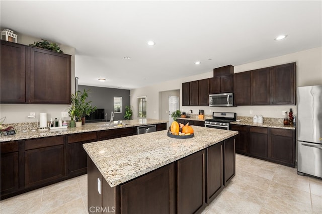 kitchen with light stone countertops, a kitchen island, recessed lighting, a sink, and stainless steel appliances