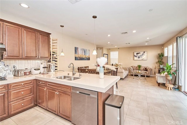 kitchen with open floor plan, a peninsula, light countertops, dishwasher, and a sink
