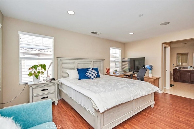 bedroom featuring recessed lighting, light wood finished floors, visible vents, and ensuite bathroom