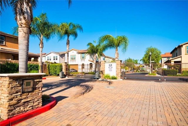 view of road with curbs, a residential view, a gated entry, and a gate