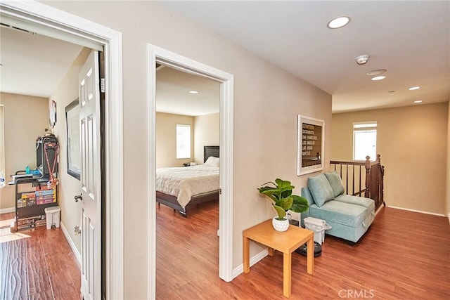 hall featuring wood finished floors, baseboards, and recessed lighting