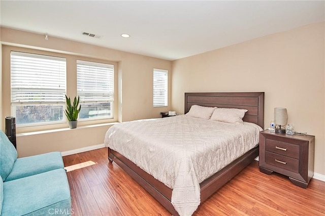 bedroom featuring visible vents, baseboards, multiple windows, and light wood-style floors