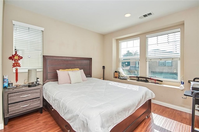 bedroom featuring wood finished floors, baseboards, and visible vents