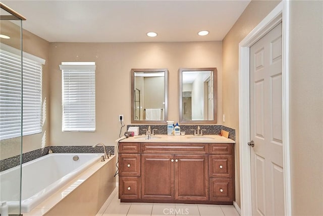 full bath featuring a bath, double vanity, a sink, and tile patterned flooring