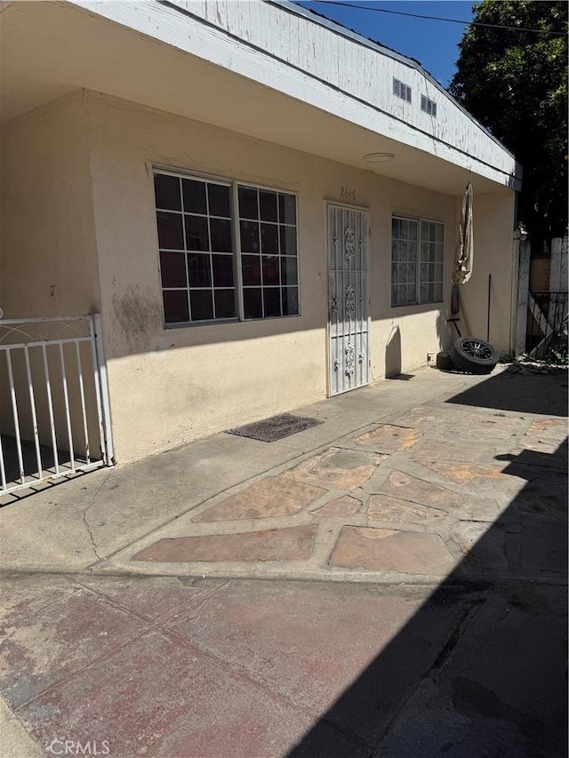 exterior space featuring a patio area, fence, and stucco siding
