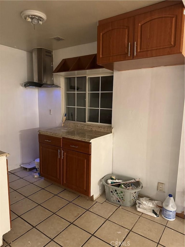 kitchen with brown cabinets, light tile patterned floors, exhaust hood, and visible vents