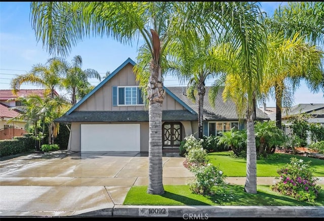 view of front facade with roof with shingles, driveway, an attached garage, and a front lawn