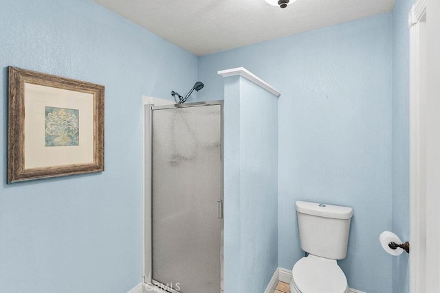 bathroom with toilet, a stall shower, and baseboards
