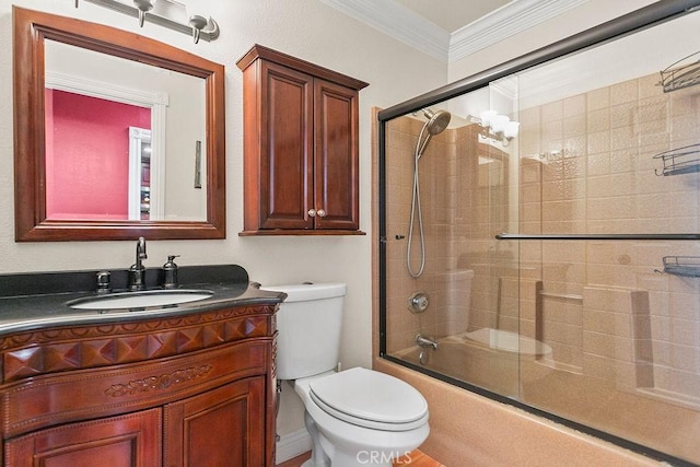 bathroom featuring toilet, vanity, ornamental molding, and bath / shower combo with glass door