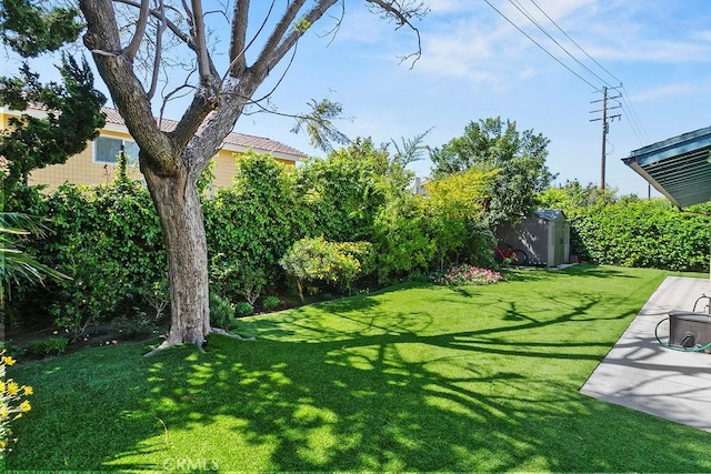 view of yard featuring a storage shed, fence, and an outdoor structure
