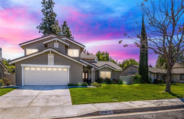 traditional home with a yard, an attached garage, and concrete driveway