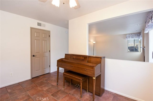 sitting room featuring visible vents, stone finish flooring, baseboards, and ceiling fan