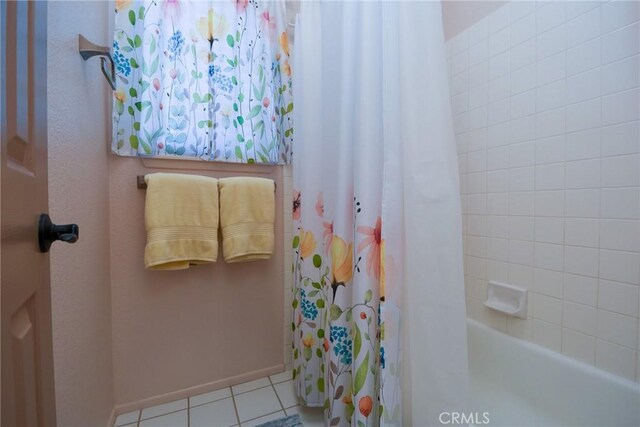 full bathroom with tile patterned floors, baseboards, and shower / bath combo with shower curtain