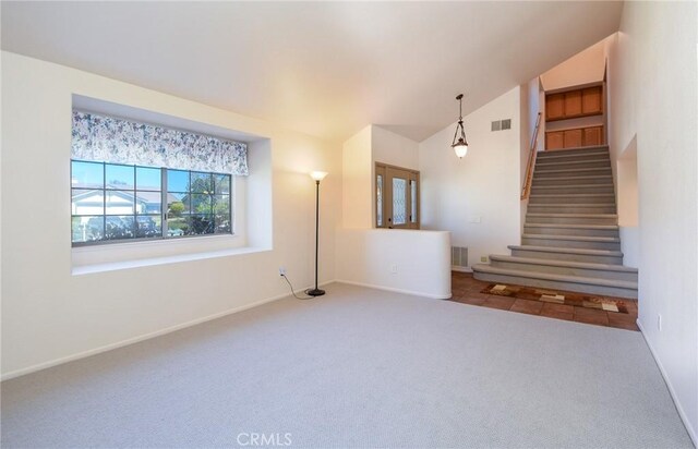 unfurnished living room with stairs, vaulted ceiling, visible vents, and carpet