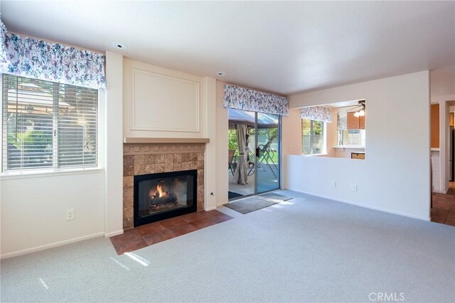 unfurnished living room with baseboards, a ceiling fan, carpet flooring, and a tile fireplace