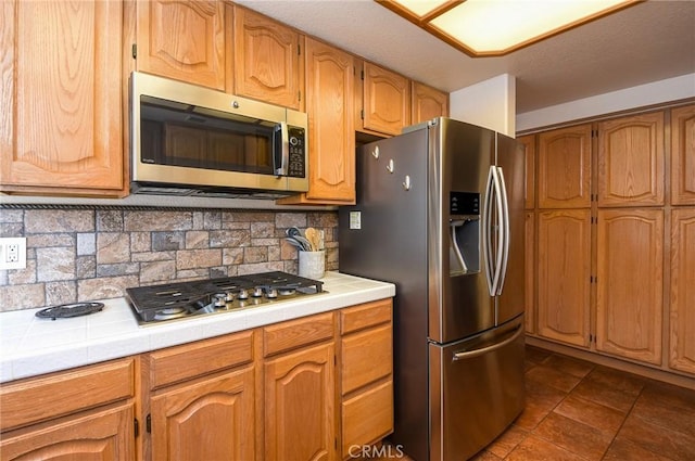 41768 Via El Greco, Temecula, CA 92592 - kitchen featuring stainless steel appliances, tile counters, backsplash, and dark tile patterned flooring