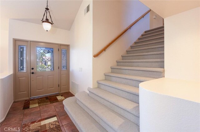 entrance foyer with visible vents, baseboards, tile patterned floors, and stairway