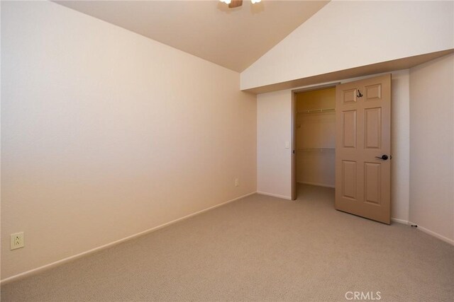 unfurnished bedroom with ceiling fan, baseboards, a closet, lofted ceiling, and light carpet