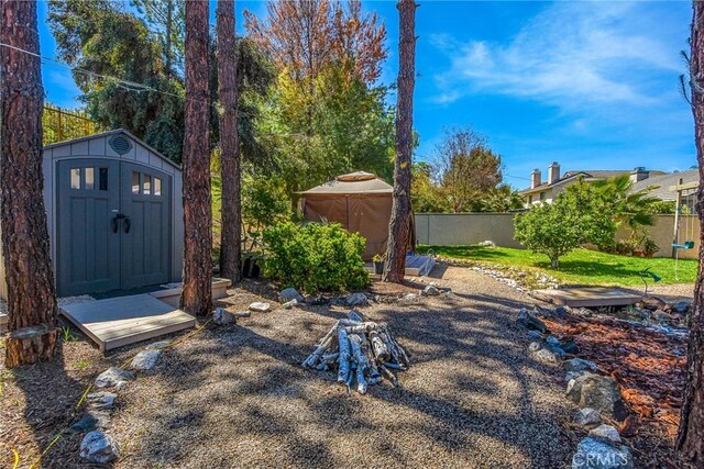 view of yard featuring a storage shed, fence, and an outbuilding