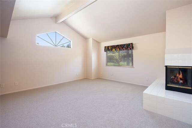 unfurnished living room featuring carpet flooring, a wealth of natural light, vaulted ceiling with beams, and a fireplace
