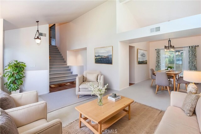 carpeted living room featuring visible vents, high vaulted ceiling, baseboards, an inviting chandelier, and stairs