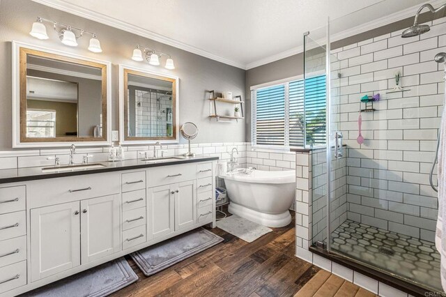full bath featuring a shower stall, ornamental molding, wood finished floors, a sink, and tile walls